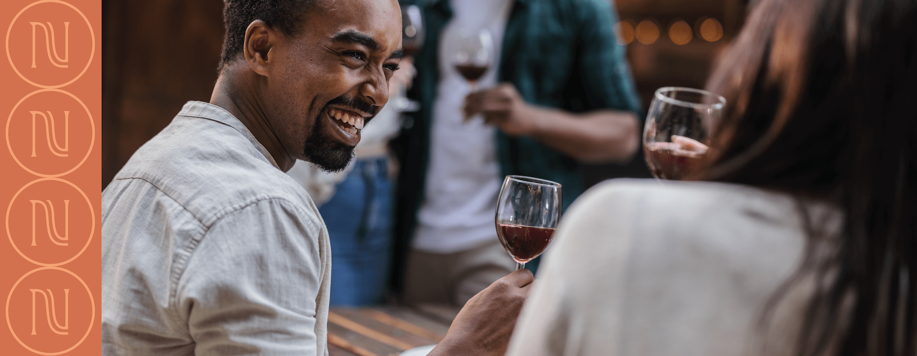 a man laughing while holding a glass of wine